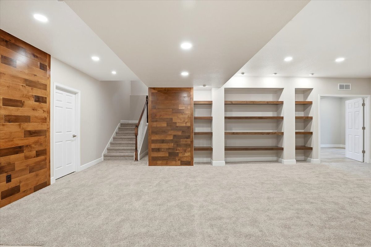 basement rec room with accent wall, hidden door, and stained shelving