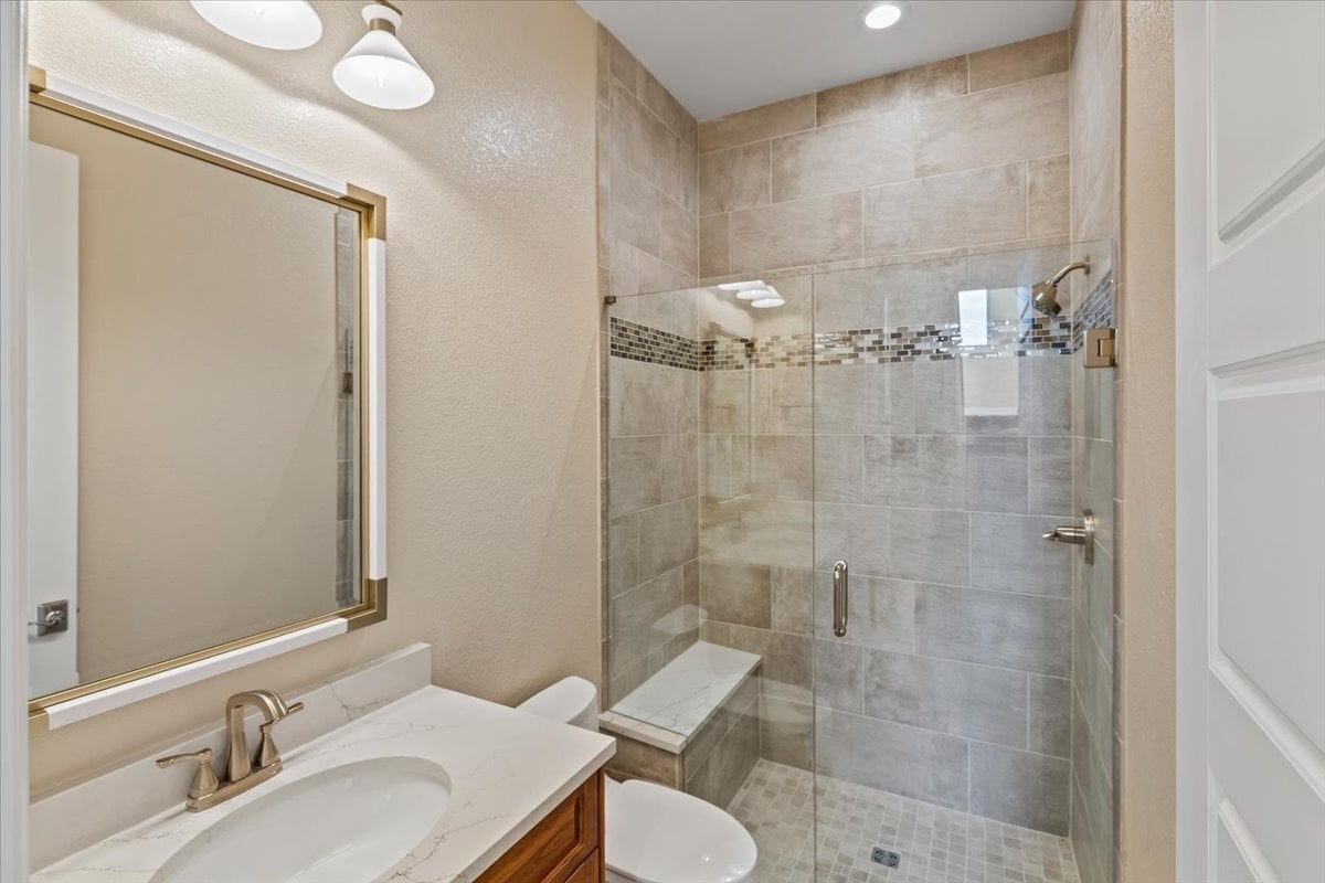 secondary bath with tiled shower and single vanity
