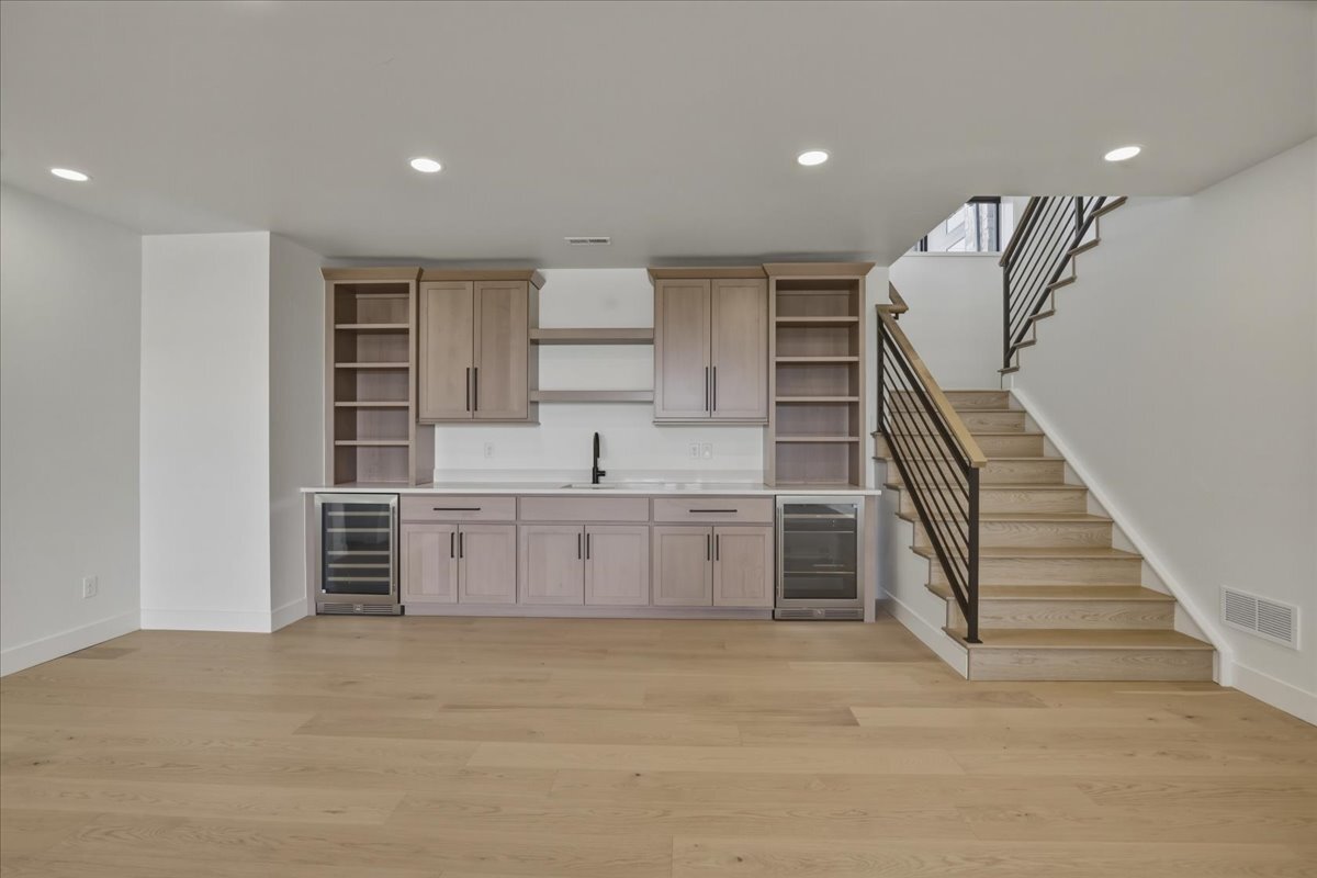 open handrail stairs leading to open rec room in walk-out basement with wet bar