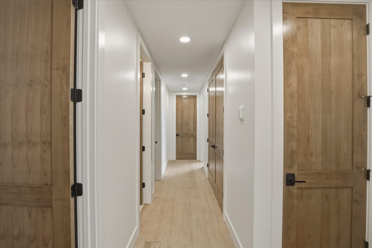 a hallway with tall, stained doors and hardwood flooring