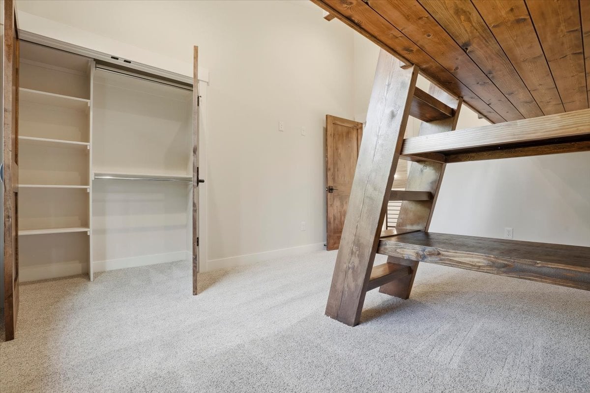 Fraser custom home - secondary bedroom, view from under built-in bunk beds showing open closet doors