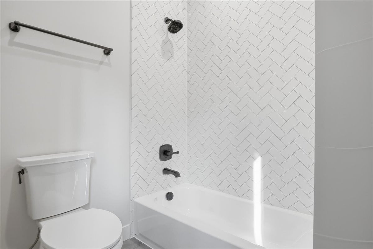 Fraser custom home - secondary bath, tub with tiled shower, herringbone subway tile