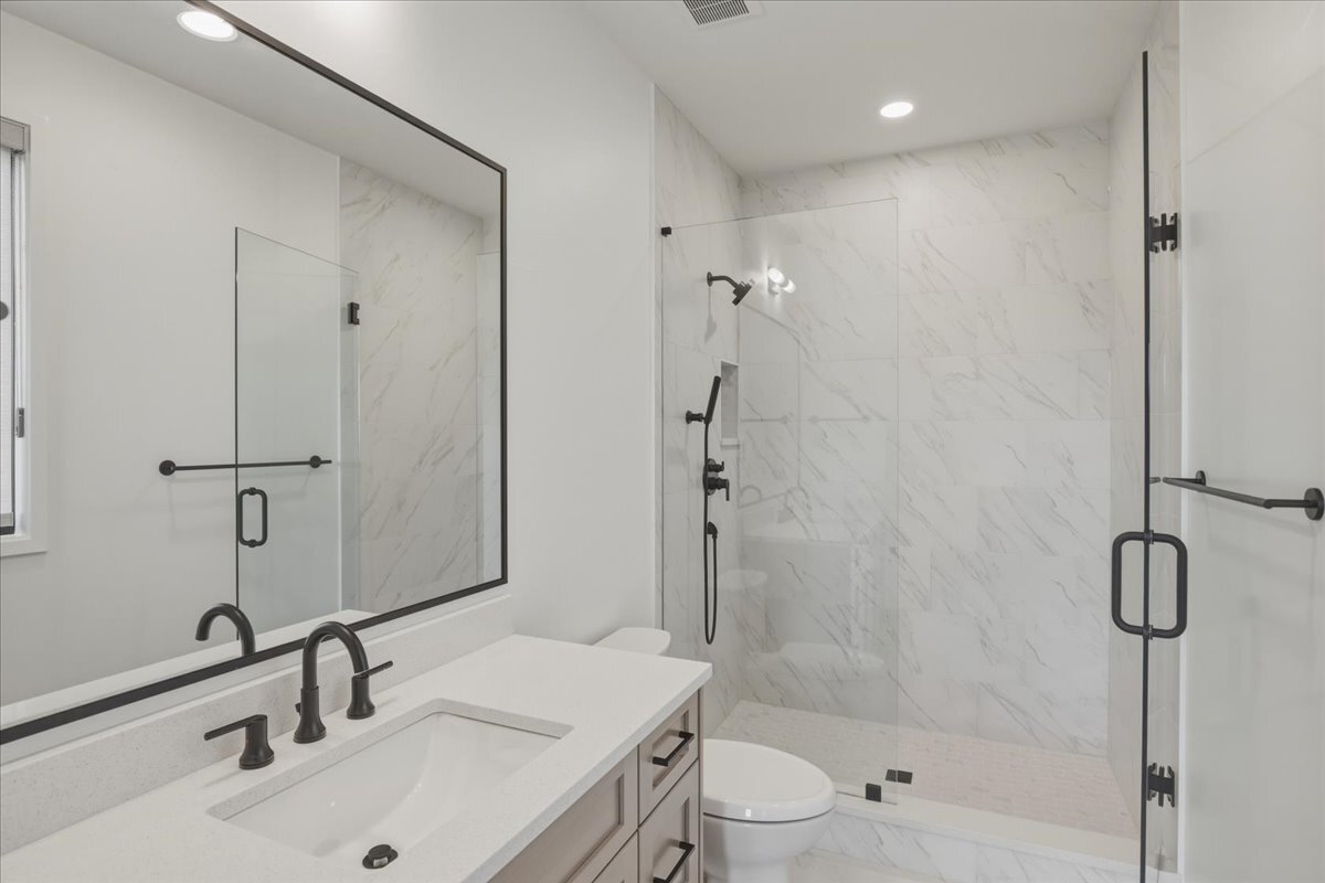 secondary bath with large shower, Euro-glass doors, and marble-look large format tile