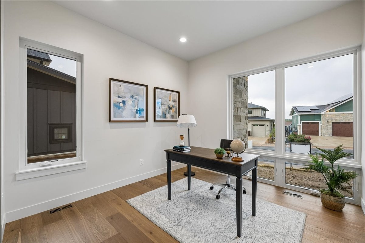 main-floor study with hardwood flooring and a large floor-to-ceiling window