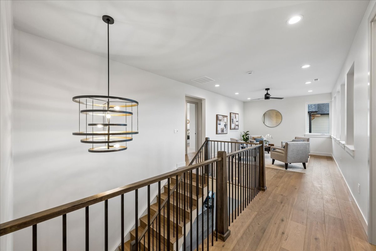 hardwood staircase leading with open handrail and designer lighting leading to second-floor loft area