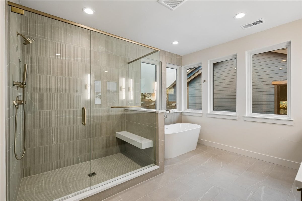 primary bath showing custom tiled over-sized shower and free-standing soaker tub