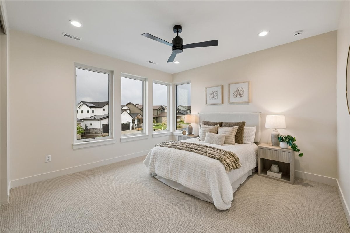 secondary bedroom with four large windows, queen--sized bed and two side tables