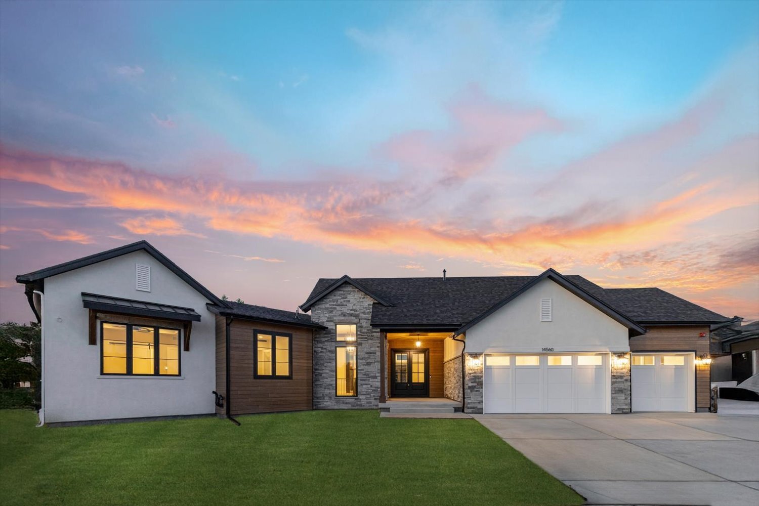 Front exterior showcasing three-car garage and sunset sky at Carr Estates Ranch custom Spec home in Westminster, CO Front exterior showcasing three-car garage and sunset sky at Carr Estates Ranch custom Spec home in Westminster, CO
