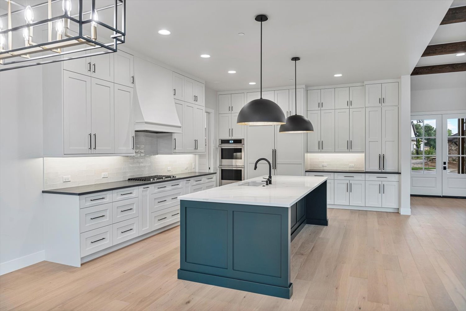 Full kitchen view in Carr Estates Ranch custom Spec home in Westminster, CO with oversized island and black pendant lighting