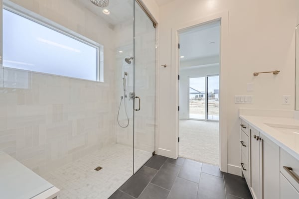 Walk-in shower with a large frosted window and elegant tilework in a custom-built home in Westminster, CO