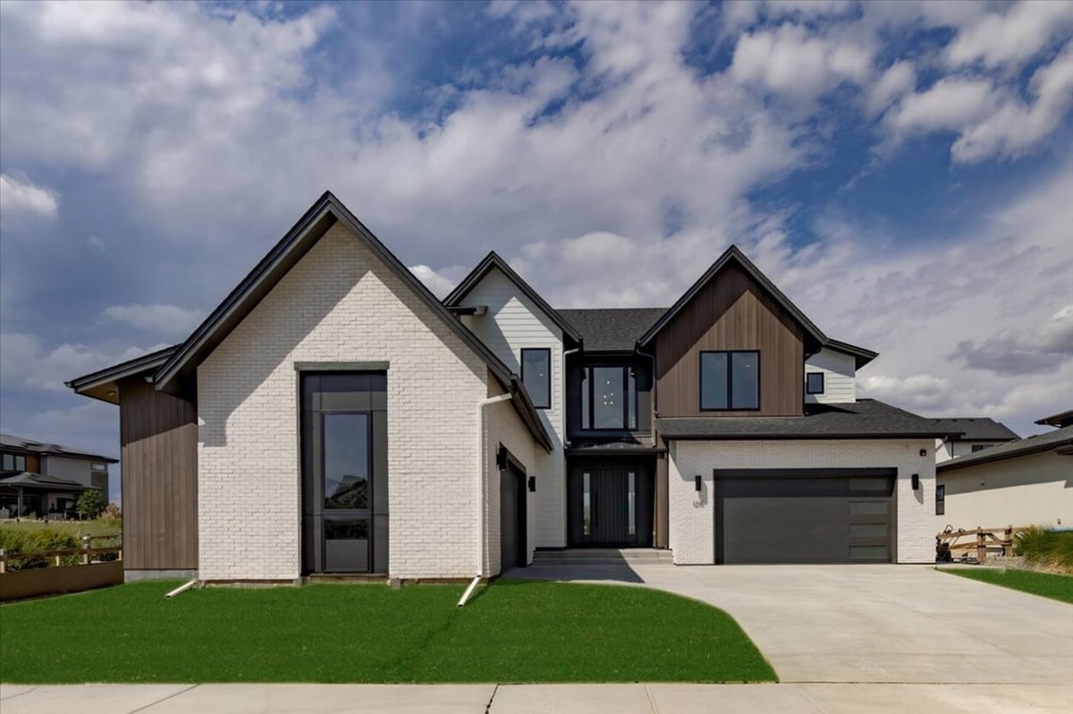 Front exterior of a Denver, CO luxury custom home featuring a modern farmhouse design with white brick and wood siding