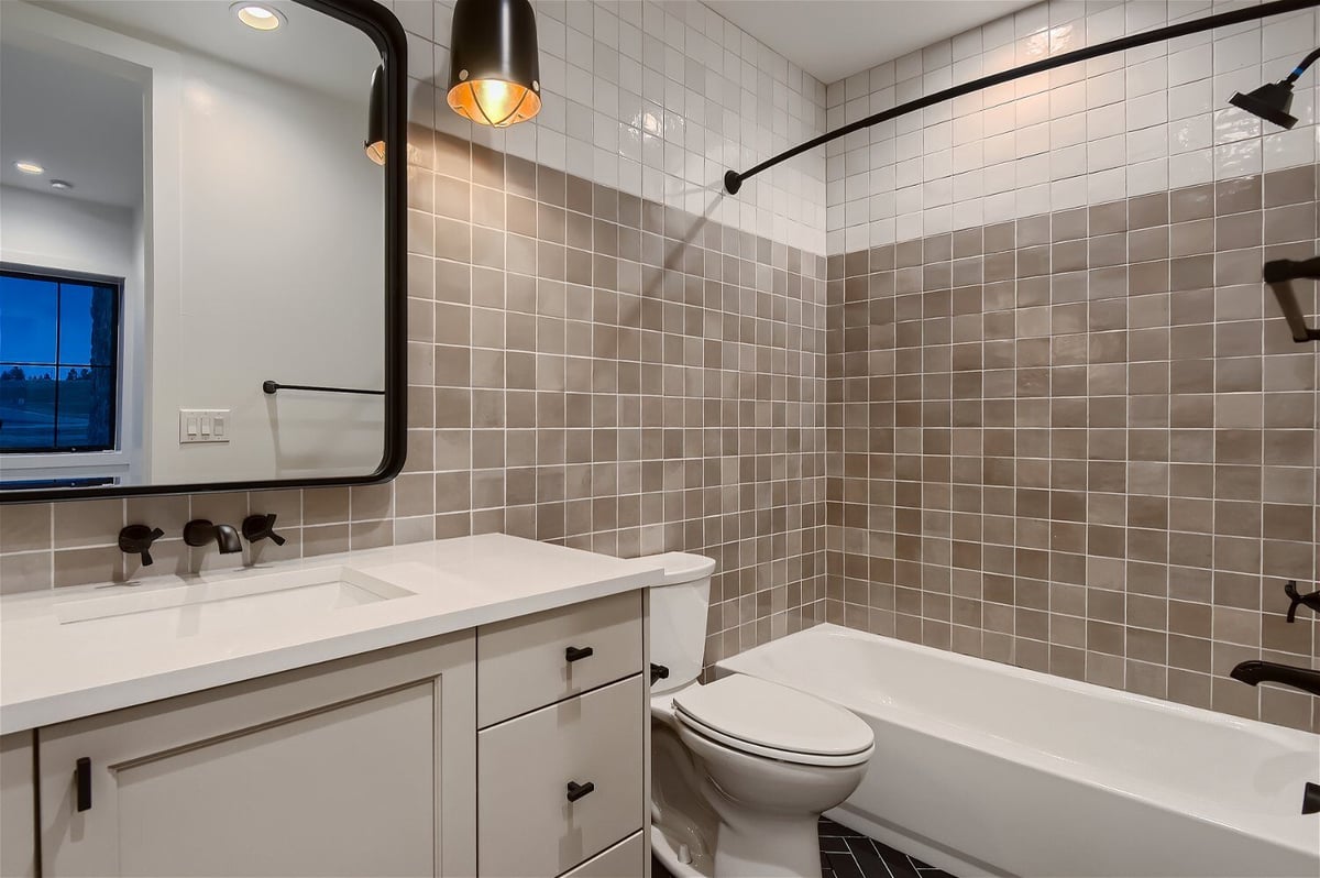 Bathroom with a wash basin, cabinetry, a toilet, and a bathtub in a custom home by Sheffield Homes in Franktown, CO