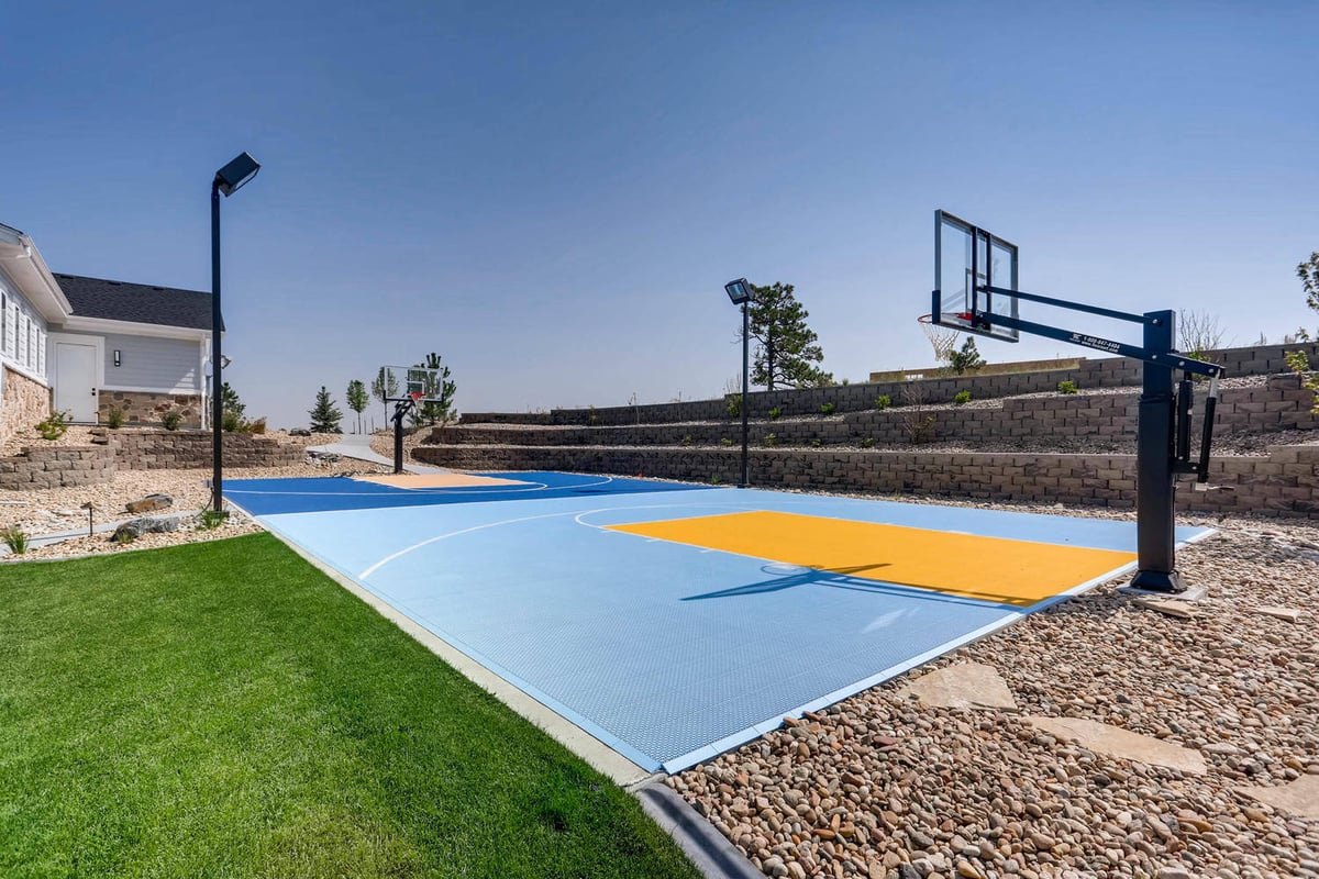 Basketball court with lighting poles outside a custom home built by Sheffield Homes in Parker, CO