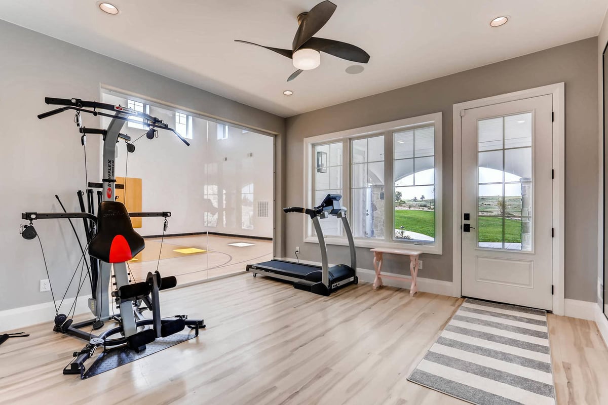 Lower-level exercise room with gym equipment in a custom home by Sheffield Homes in Parker, CO