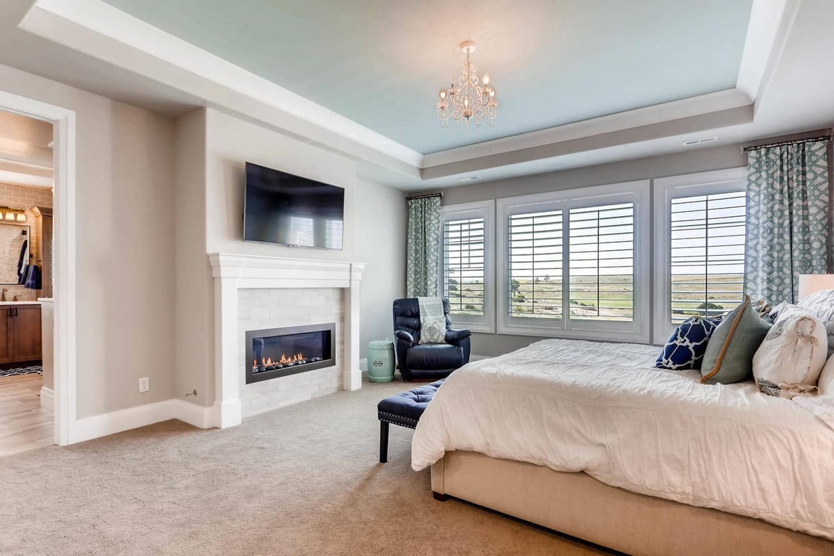 Premium master bedroom with sliding windows, a fireplace, and a wall-mounted LED TV in a Sheffield Homes home in Parker, CO