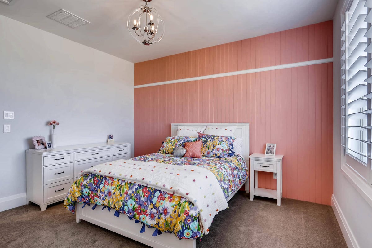 Second-floor bedroom featuring a dusty rose color wall, a side table, and a dresser in a Sheffield Homes home in Parker, CO