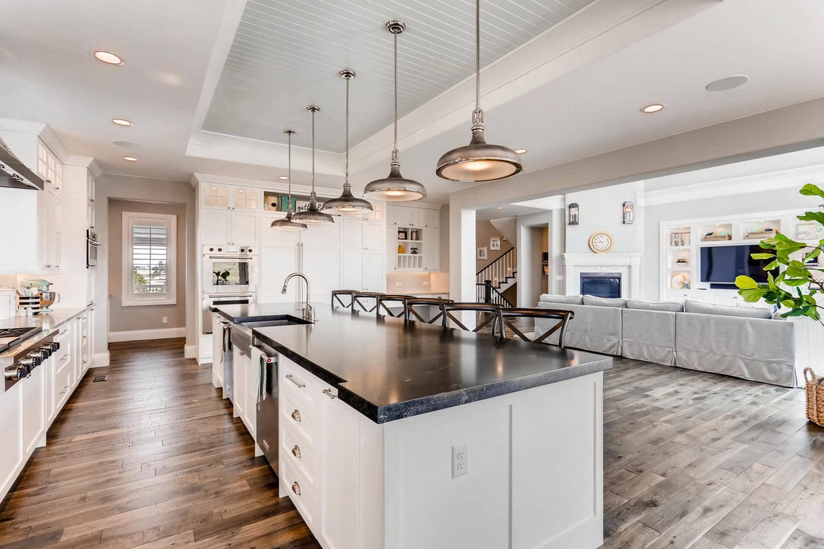 Side view of the kitchen island with seating, and elegant pendant lighting in a custom home by Sheffield Homes in Parker, CO