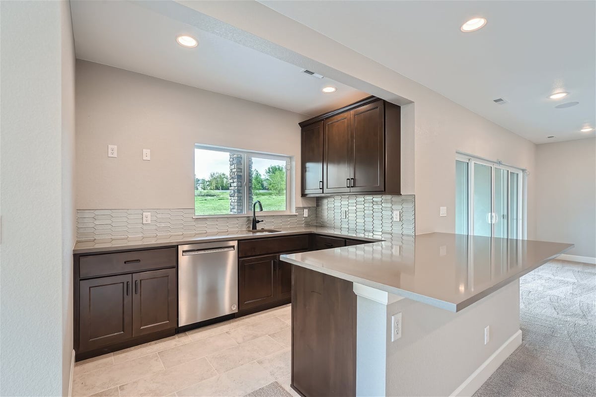 Lower-level wetbar with natural wooden color cabinetry, and a central counter in a Sheffield Homes home in Superior, CO