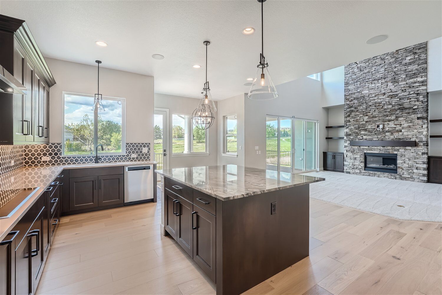 Open kitchen with a central island, pendant lighting, and wooden cabinetry around in a Sheffield Homes home in Superior, CO