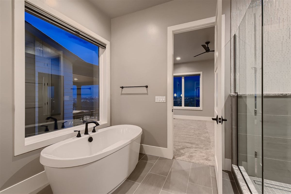 Freestanding bathtub with scenic window views in the primary bathroom of a Sheffield Homes custom home, Denver, CO