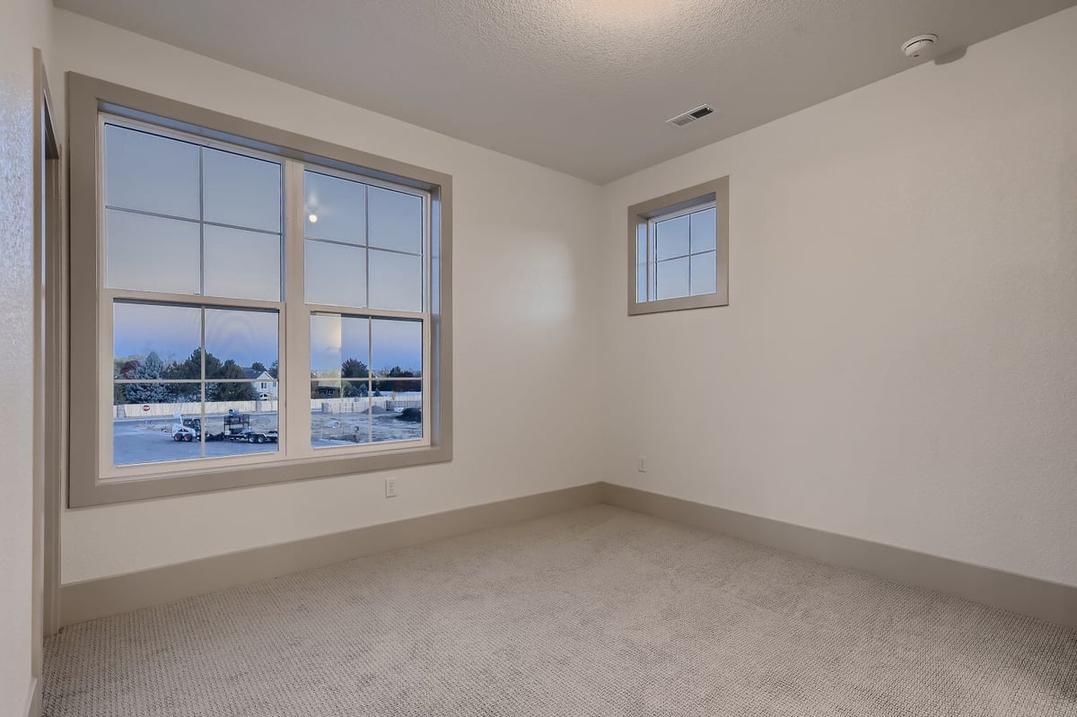 Second-floor bedroom with carpet flooring, a large sliding window for outdoor views, by Sheffield Homes in Westminster, CO