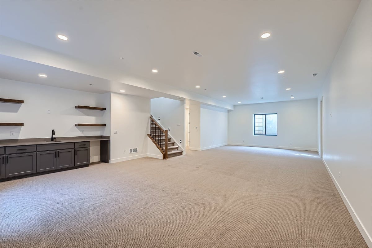 Lower-level family room with carpet flooring, recessed lights, and a corner bar in a Sheffield Homes home in Westminster, CO