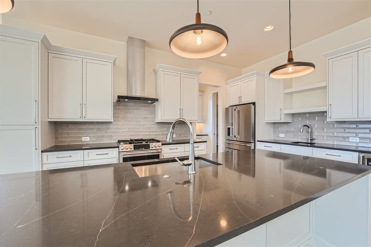 Kitchen island featuring a marble countertop and a silver faucet in a home by Sheffield Homes in Westminster, CO