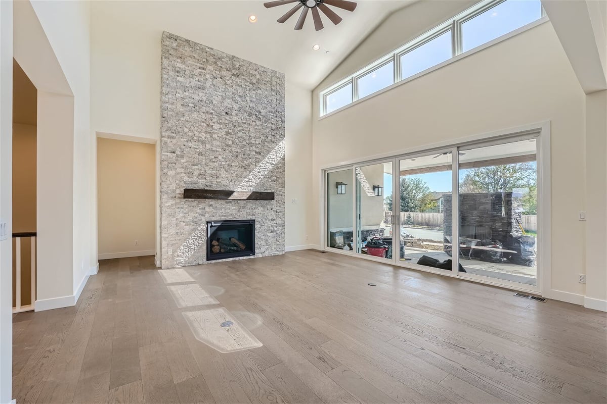 Living room with sliding doors, a corner fireplace, and a ceiling fan in a Sheffield Homes home in Westminster, CO