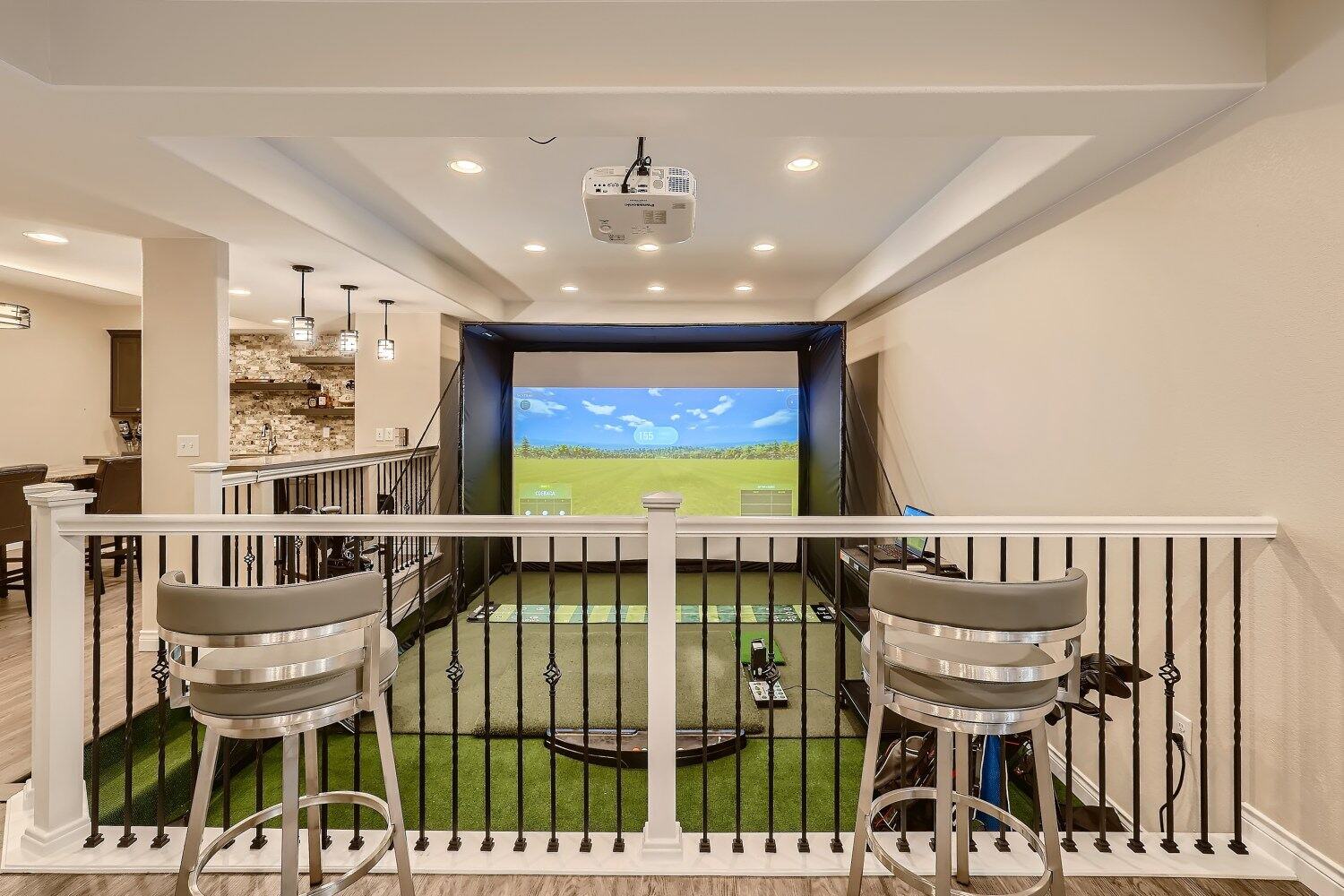 Lower-level golf simulator setup in a custom home by Sheffield Homes in Arvada, CO, featuring a projector screen and elevated seating area (1)