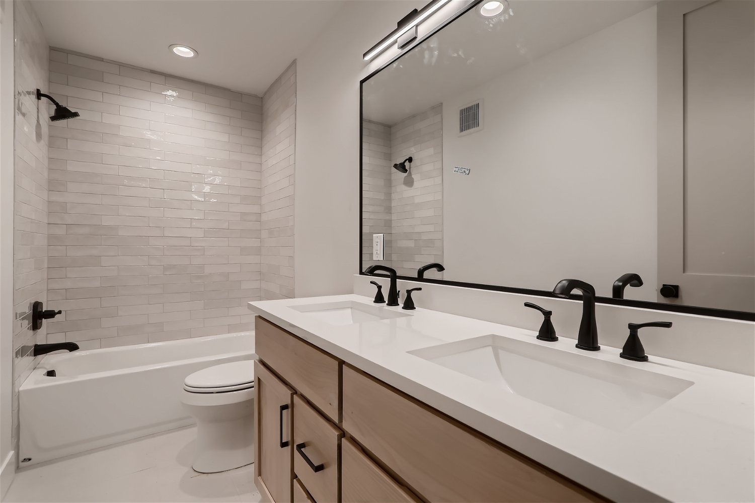 Modern basement bathroom with dual sinks and subway tile walls by Sheffield Homes in Denver, CO