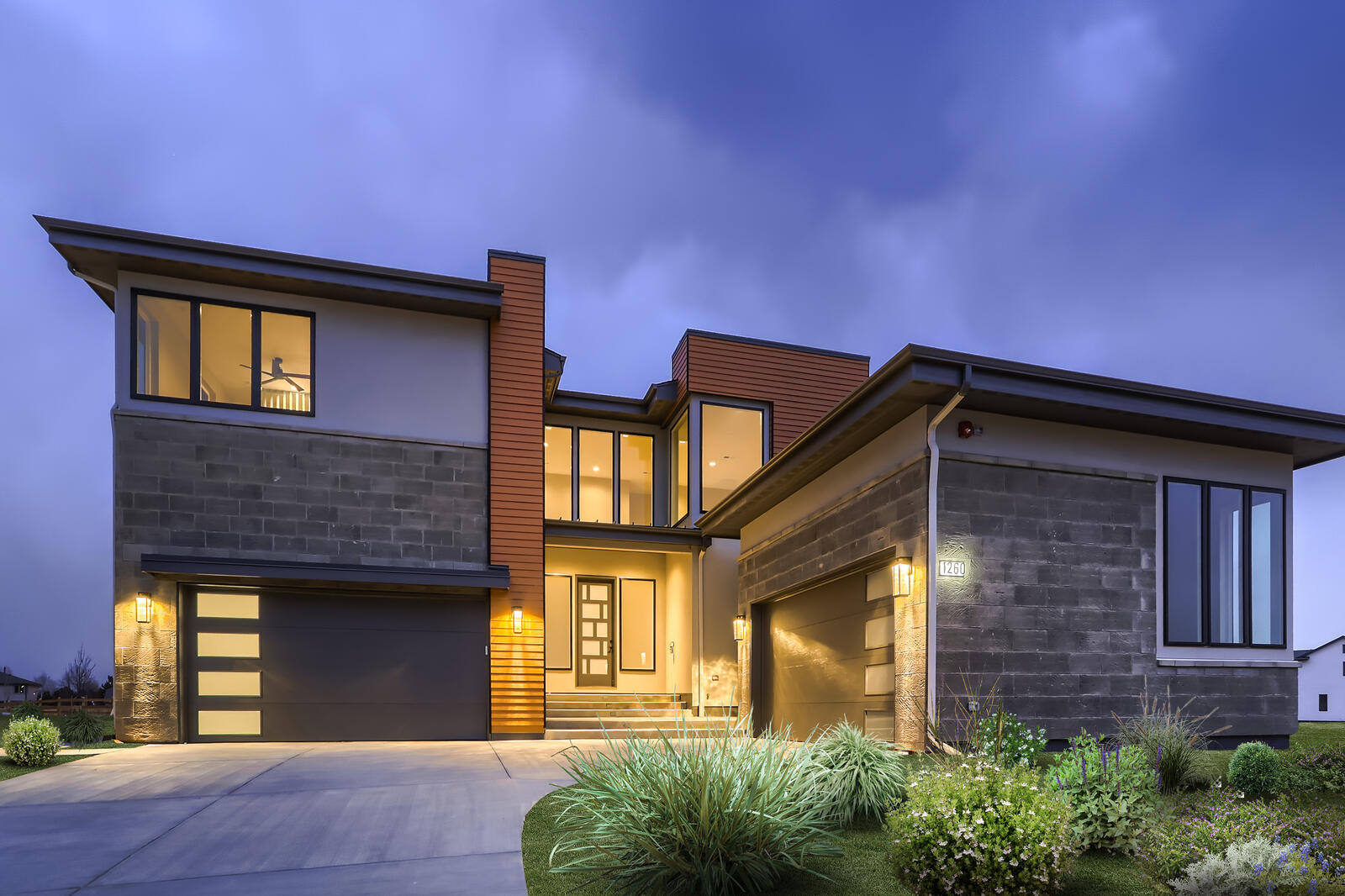 Modern custom home exterior by Sheffield Homes in Denver, CO, illuminated at dusk with sleek architectural design