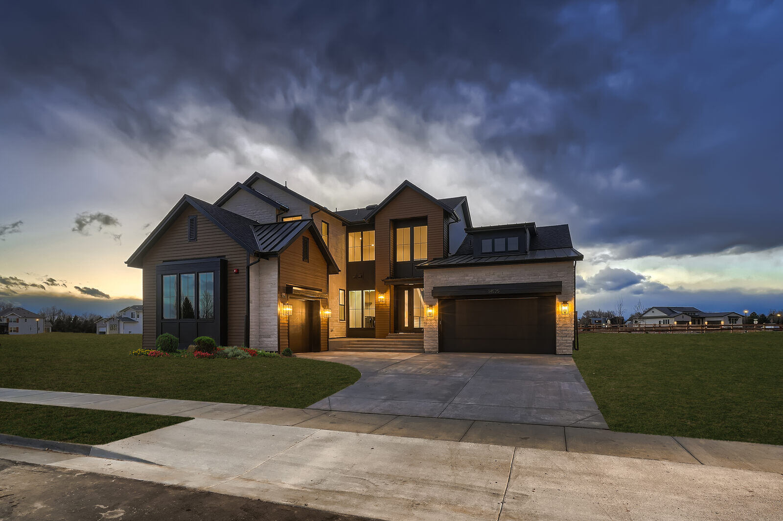 Newly built luxury home exterior by Sheffield Homes in Denver, CO, with illuminated entryway at dusk