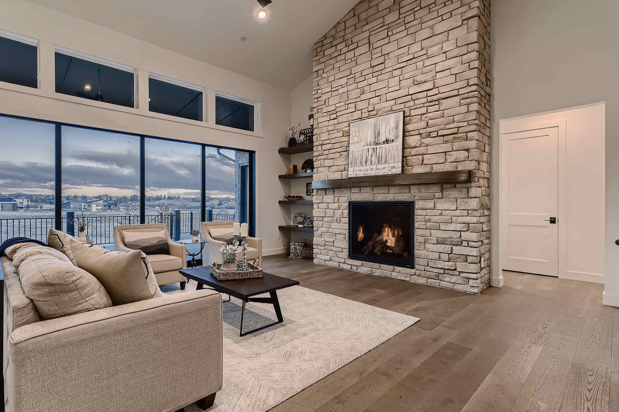 Spacious living room with large windows and stone fireplace in a Sheffield Homes custom home in Arvada, CO