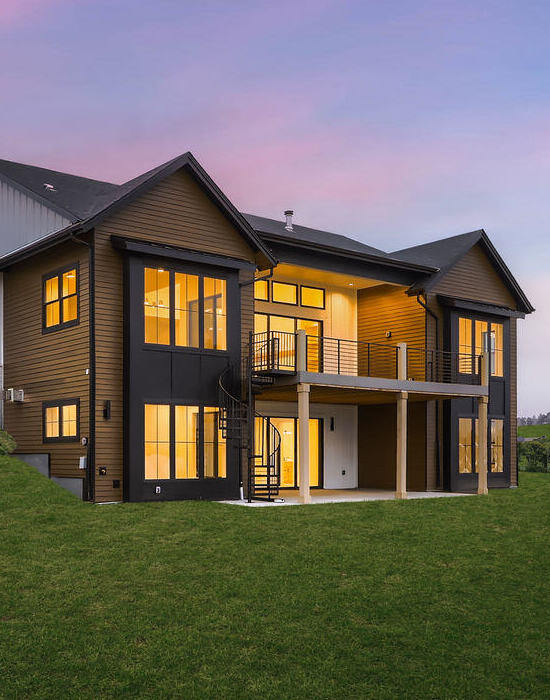 Rear view of a custom home by Sheffield Homes in Denver, CO, showcasing a large deck and expansive lawn under a serene evening sky (2)