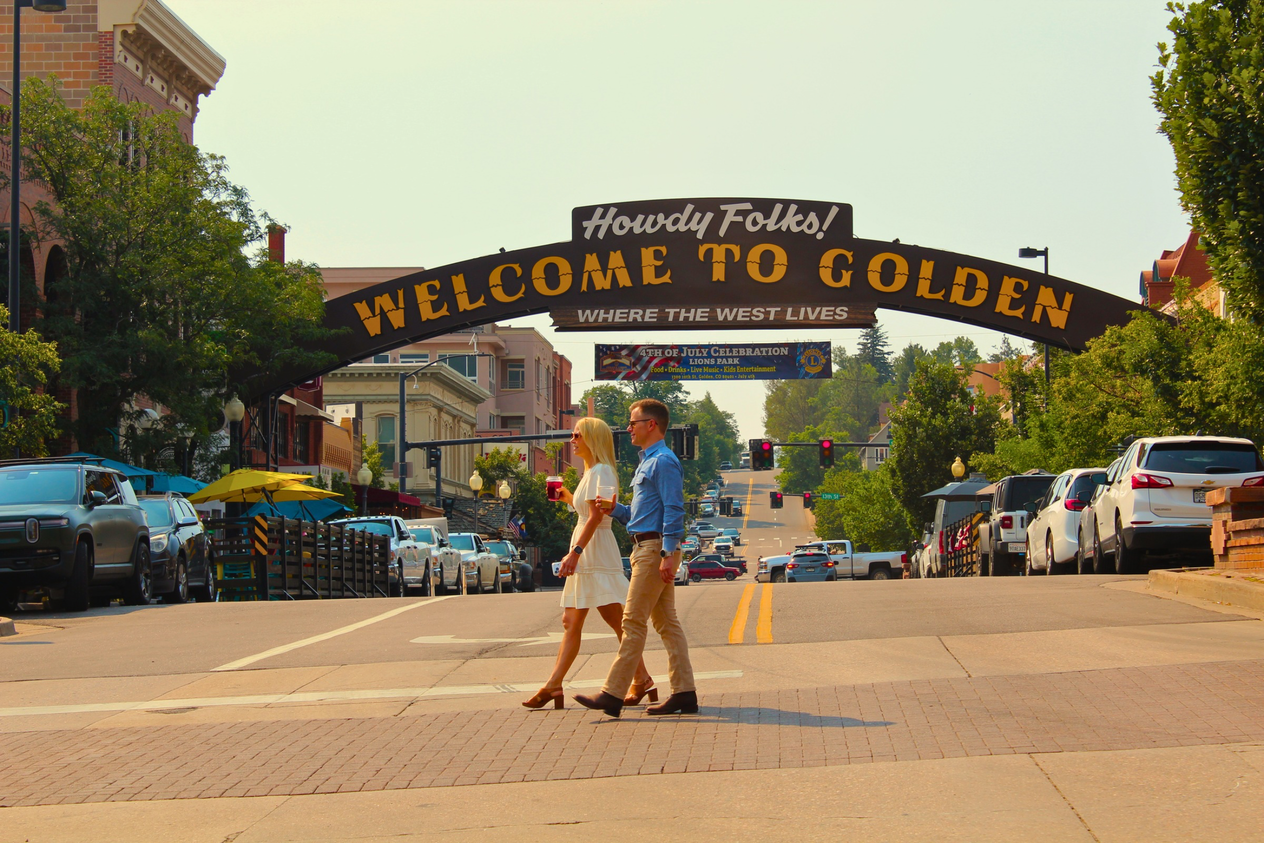 Two people walking in downtown Golden, CO under the welcome arch