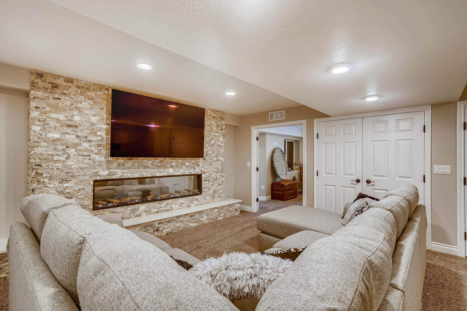 Modern basement family room with large sectional and fireplace, part of a basement renovation by Sheffield Homes in Arvada, CO