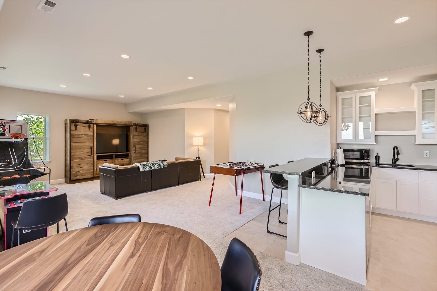 Modern family room with built-in entertainment center and game tables, basement remodel by Sheffield Homes in Arvada, CO