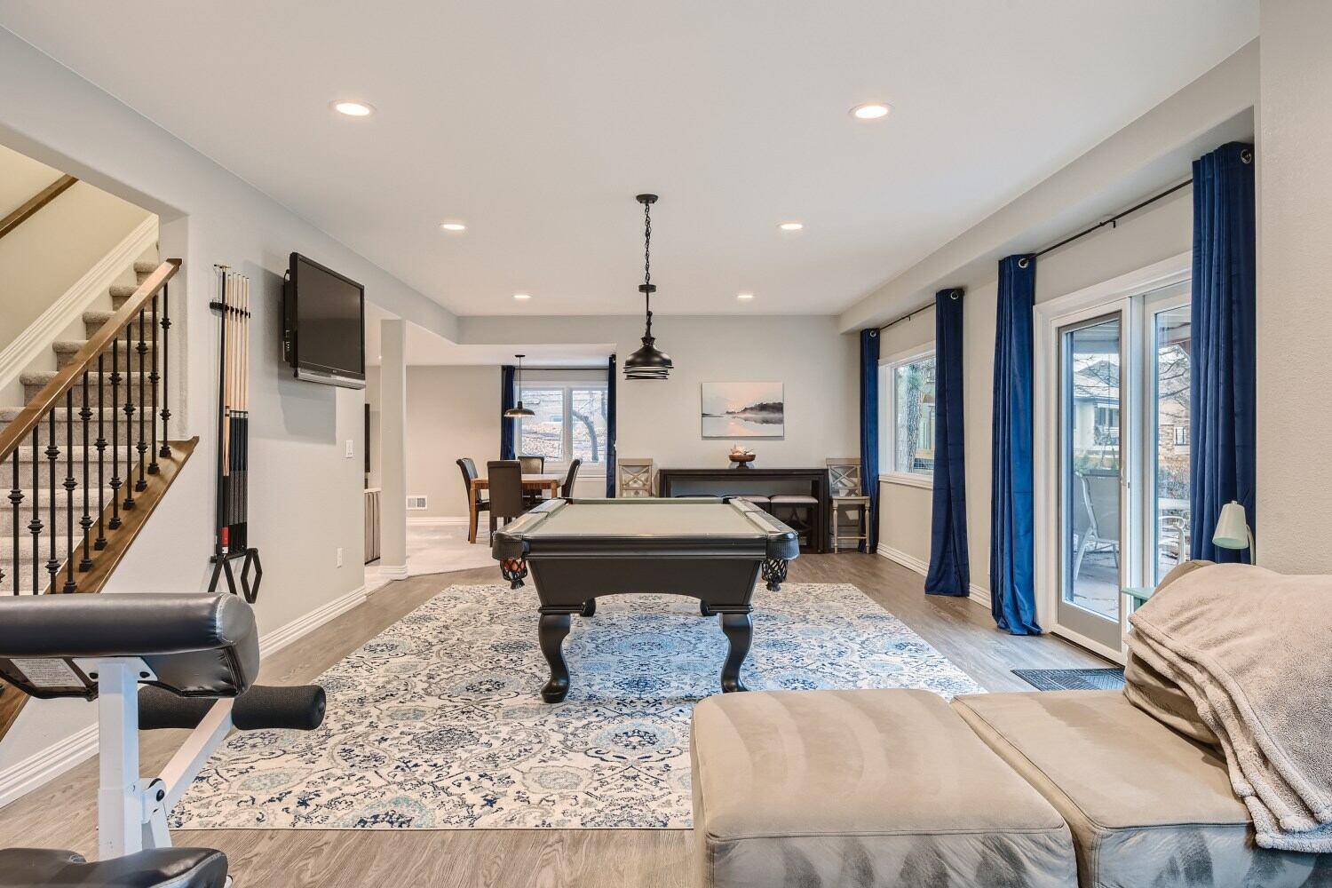 Pool table and entertainment area in a finished basement with seating and windows, Littleton, CO by Sheffield Homes