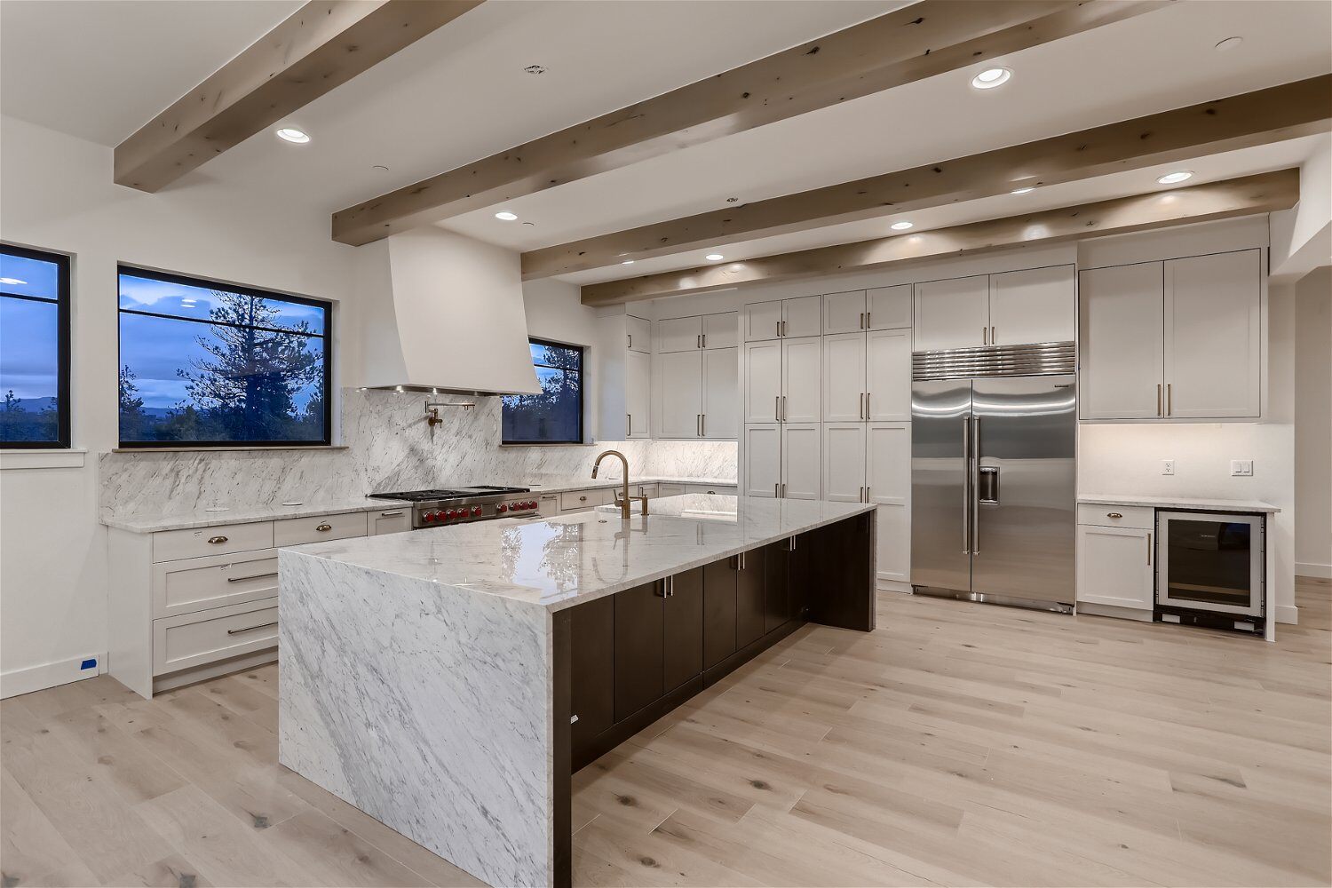 Modern white-themed kitchen with a unique island, stove, and cabinetry in a custom home by Sheffield Homes in Evergreen, CO