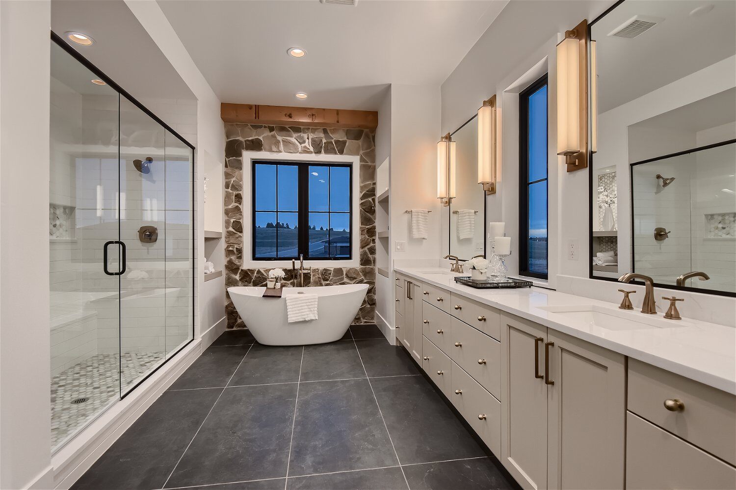 Main bathroom with marble flooring, a bathtub, shower, and dual vanities in a custom home by Sheffield Homes in Franktown, CO