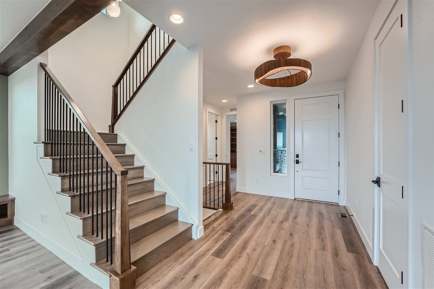 Wood texture flooring in the foyer and stairways, with white room doors in a custom home by Sheffield Homes in Louisville, CO