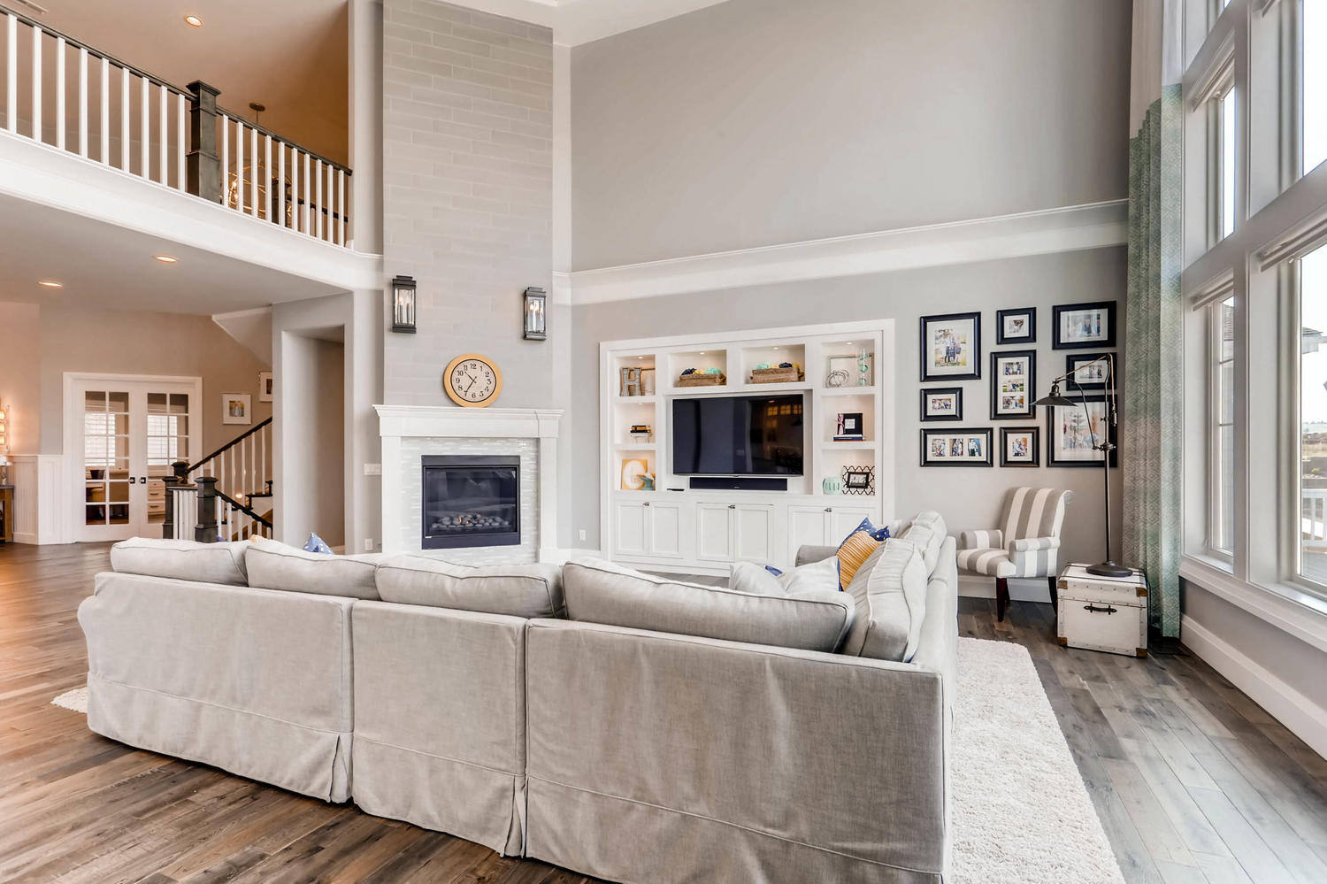 Ground floor family hall with large sofas, a fireplace, and a front wall LED TV in a home by Sheffield Homes in Parker, CO