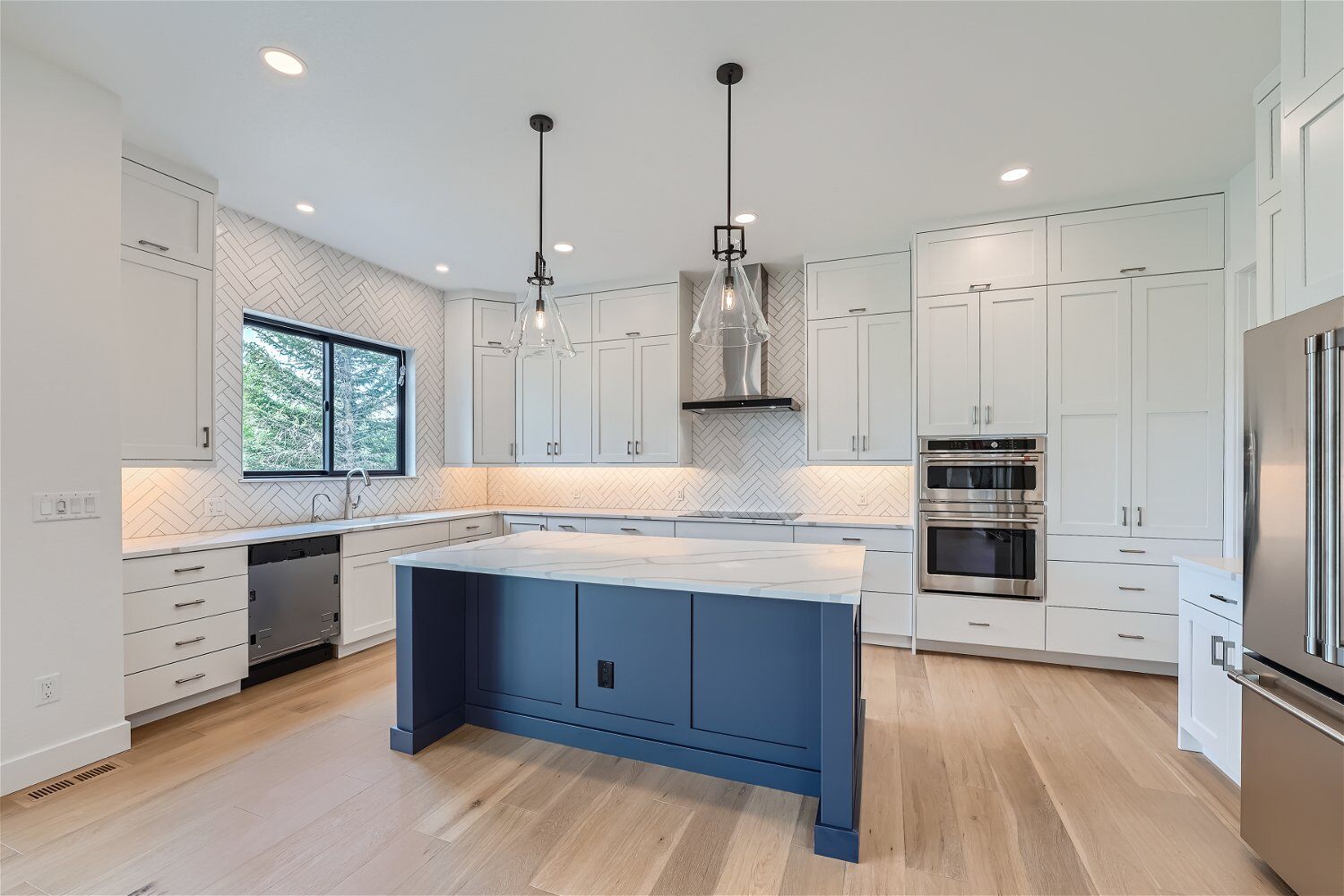 Kitchen with a central counter featuring blue and white cabinets and pendant lighting in a Sheffield Homes home, Superior, CO