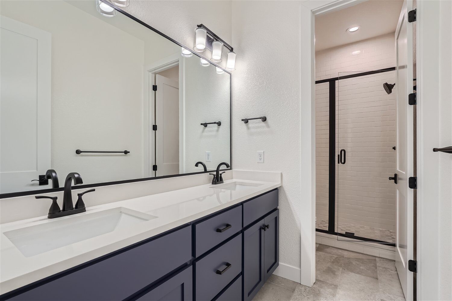 Bathroom with a dual basin faucet, a large mirror, and a separate shower area in a Sheffield Homes home in Superior, CO