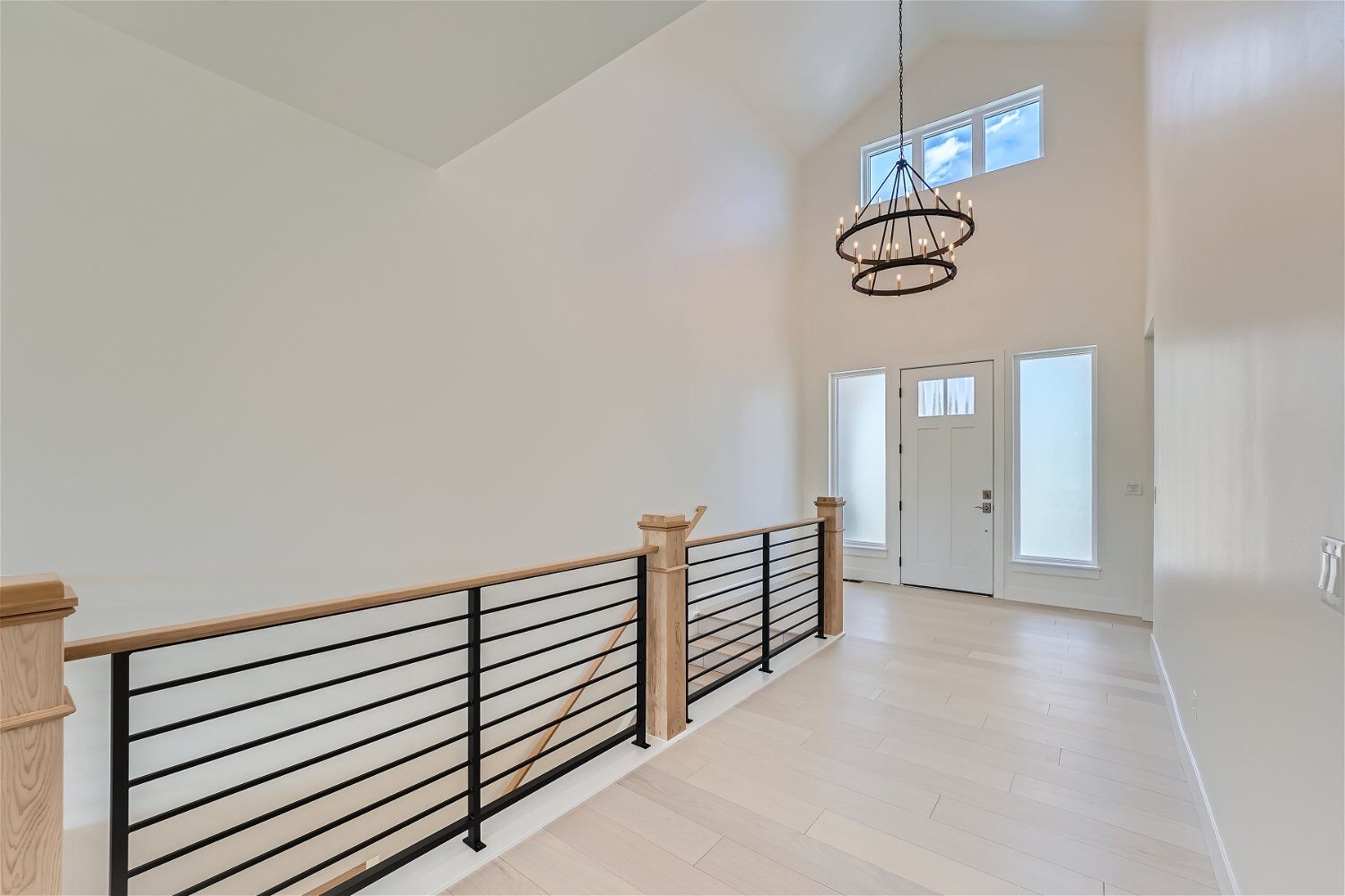 Foyer featuring an elegant chandelier, with metal and wood railings, in a custom home by Sheffield Homes in Superior, CO