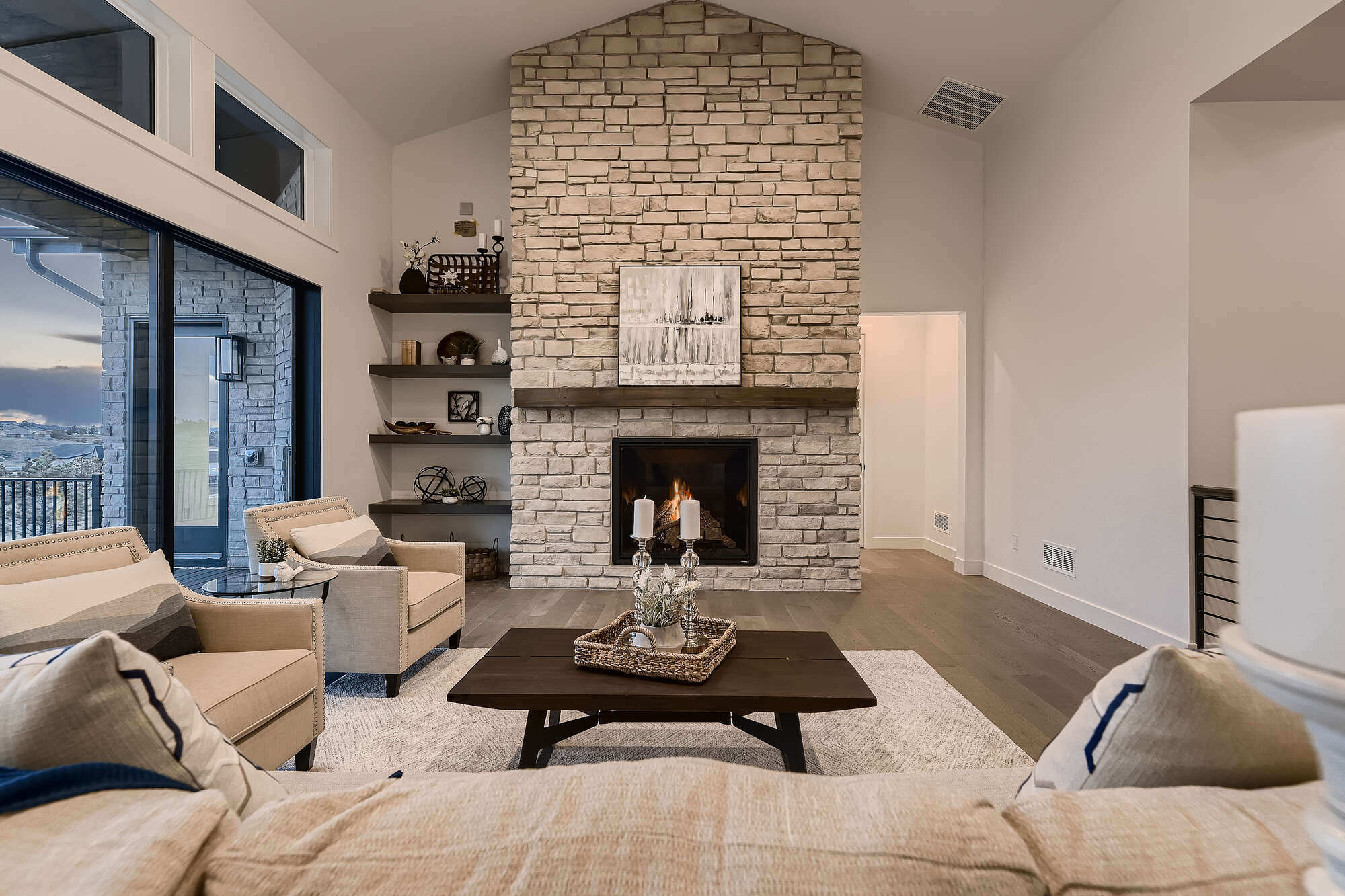 Living room with a modern stone fireplace and expansive windows in a Sheffield Homes custom home in Arvada, CO