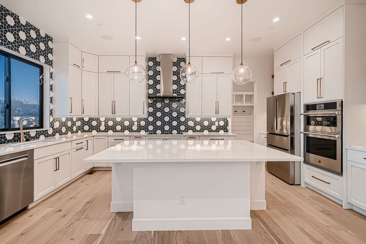 Large kitchen island centered beneath modern glass pendants in custom home by Sheffield Homes in Denver, CO Large kitchen island centered beneath modern glass pendants in custom home by Sheffield Homes in Denver, CO